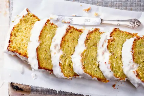 Saftiger Zucchini Kuchen mit weißer Glasur, in Scheiben geschnitten, bereit zum Genießen.