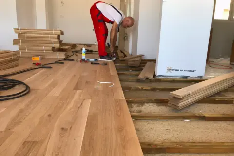 Instalador coloca elondo madera en un suelo.