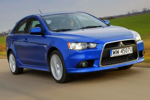 Niebieski Mitsubishi Lancer 9 w ruchu, z widocznym kierowcą i polskimi tablicami rejestracyjnymi.