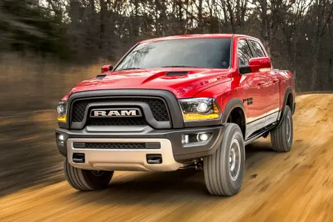 Czerwony Dodge Ram Rebel pędzi po leśnej drodze. Poznaj jego imponujące dodge ram wymiary i możliwości terenowe.