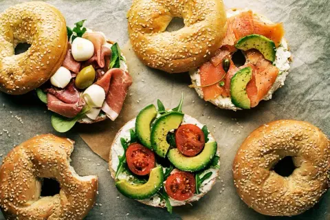 Pyszne bajgle z łososiem, awokado, pomidorkami, mozzarellą i szynką. Idealne co zamiast chleba na śniadanie lub lunch.
