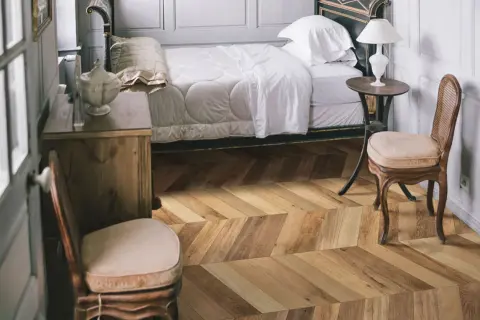 Sypialnia z łóżkiem i meblami, podłoga w jodełkę z kolekcji Marazzi Treverksoul Neutral.