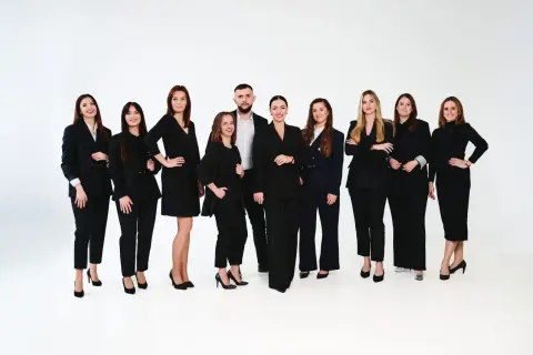 Grupa profesjonalistów w czarnych garniturach na białym tle.