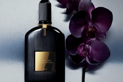 Elegancka butelka perfum Tom Ford Black Orchid 100ml obok ciemnofioletowych storczyków.