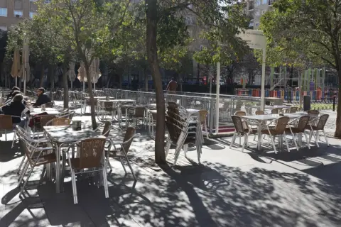 Mesas y sillas vacías en la terraza de bares de la plaza San Francisco, bajo la sombra de los árboles.