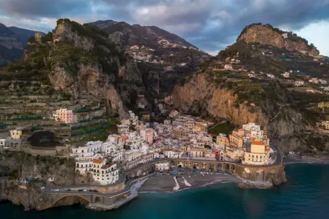 Un borgo pittoresco sulla Costiera Amalfitana, tra i paesi più belli d'Italia, aggrappato alla roccia con case colorate e mare blu.
