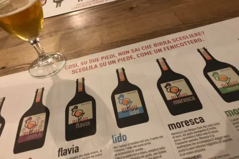 Un bicchiere di birra e un menu del birrificio Rubiu con diverse etichette di birra.