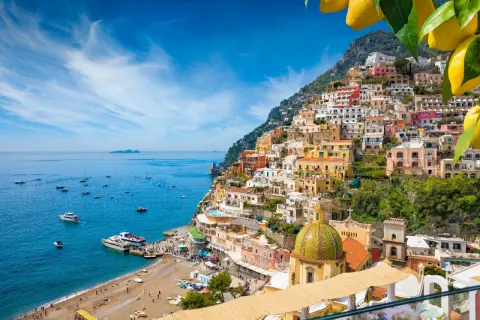 Positano, un gioiello da scoprire tra le cose da visitare in Campania. Case colorate a picco sul mare blu, barche e una spiaggia vivace.