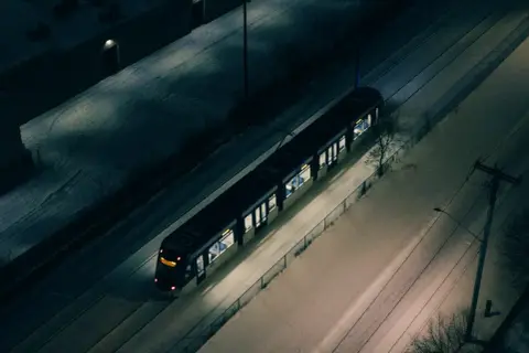 Pociąg Warszawskiej Kolei Dojazdowej mija ośnieżone tereny nocą.
