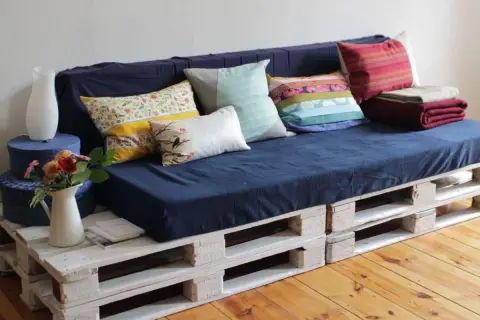 Sofá hecho como hacer un sofa con palets, con cojines coloridos y mantas.