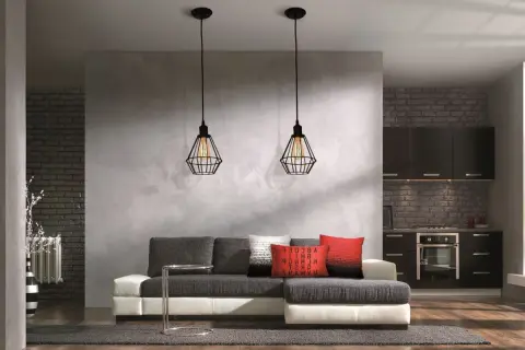 Nowoczesna ściana działowa z betonową fakturą oddziela salon od kuchni. Dwa industrialne lampy wiszące nad kanapą.