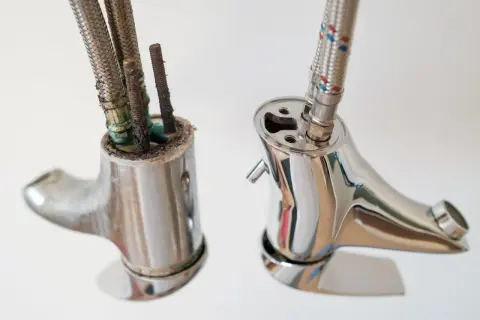 Stary, skorodowany kran obok nowego, lśniącego. Wymiana głowicy w baterii dwuuchwytowej to prosty sposób na odświeżenie łazienki.