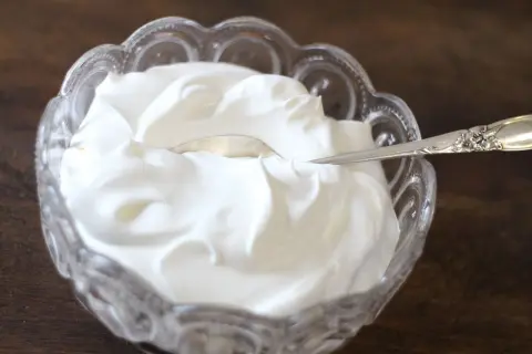 Gęsta, biała śmietana w kryształowej miseczce. Czy to creme fraiche? Tak, to właśnie creme fraiche, idealna do deserów i sosów.