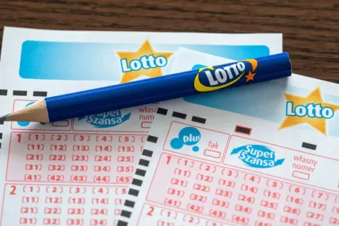 Niebieski ołówek na kuponach Lotto z zaznaczonymi polami do wyboru liczb.