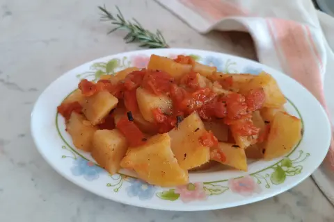 Patate in umido con pomodoro e rosmarino, un piatto semplice e gustoso, servito su un piatto fiorato.