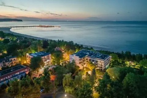 Widok z lotu ptaka na nadmorskie apartamenty i molo o zmierzchu.