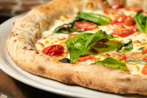 Pyszna pizza Margherita, klasyk kuchni włoskiej, z pomidorkami, mozzarellą i bazylią. Idealna pizza wlochy.
