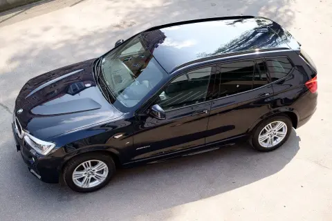 Ciemnogranatowy SUV BMW X3, samochód który mało pali, stoi na parkingu.