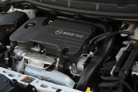 Silnik Opel Astra 1.4 Turbo Ecotec. Widoczny turbosprężarka, kolektor dolotowy i osłona silnika.