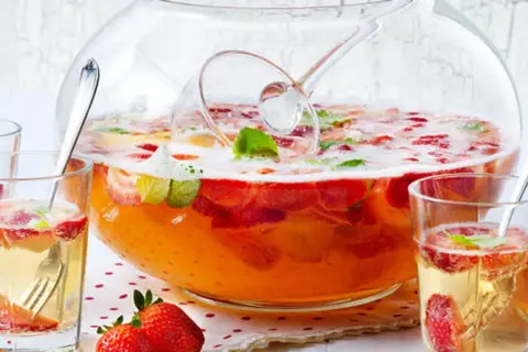 Erfrischendes Bowle-Rezept mit Erdbeeren und Minze in einer großen Glasbowle, bereit zum Servieren in Gläsern.