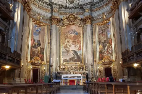 Interno della chiesa di Sant'Ignazio di Loyola, con affreschi barocchi, altare dorato e panche in legno.