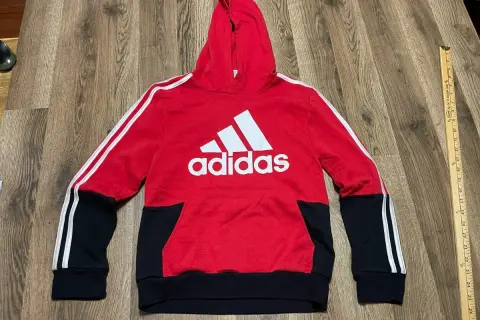 Czerwona bluza z kapturem Adidas dla chłopca z białym logo i czarnymi wstawkami.