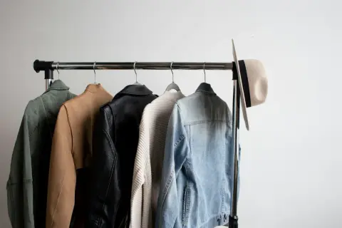 Jacken und ein Hut auf einer Kleiderstange, perfekt für einen casual chic sommer Look.