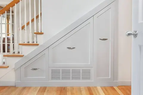 Solución inteligente para hacer armario bajo escalera. Muebles blancos a medida aprovechan cada rincón.