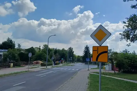 Znak drogowy informuje o pierwszeństwie przejazdu i możliwości omijania przeszkody po prawej stronie.