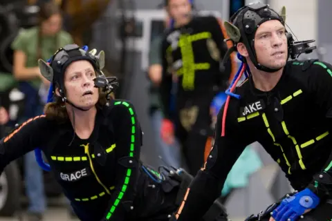 Aktorzy w strojach do motion capture, z markerami na twarzach i ciałach, przygotowują się do sceny.