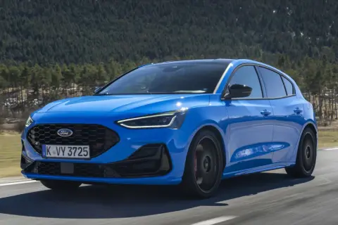 Niebieski Ford Focus ST na drodze, zalesione wzgórza w tle.