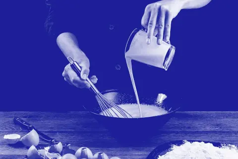 Manos mezclando diferentes tipos de leche en un bol. Huevos rotos y harina en la mesa.