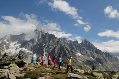 Groupe de randonneurs profitant d'une magnifique randonnée à Chamonix, avec des montagnes imposantes en arrière-plan.
