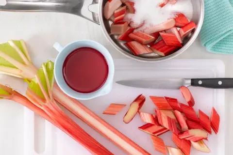 Frischer Rhabarber wird geschnitten und mit Zucker für ein leckeres Rhabarberkompott vorbereitet.