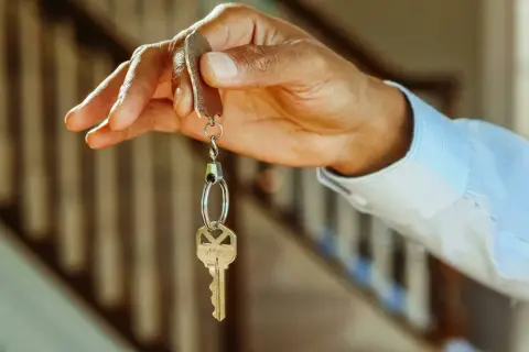 Chiave di casa tenuta in mano, simbolo di un immobile intestato ad un solo coniuge in comunione dei beni.