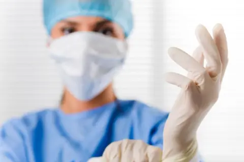 Ärztin zieht Handschuhe an. Der PSA-Wert ist wichtig für die Sicherheit.
