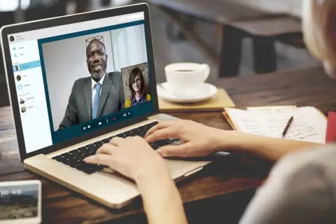 Kobieta prowadzi rozmowę przez Skype z dwoma współpracownikami.