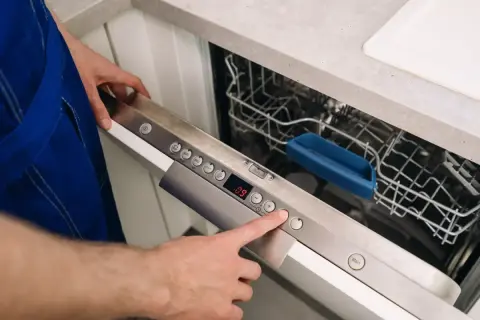 Ręka naciska przycisk na panelu zmywarki Whirlpool, pokazując, jak zresetować zmywarkę Whirlpool.