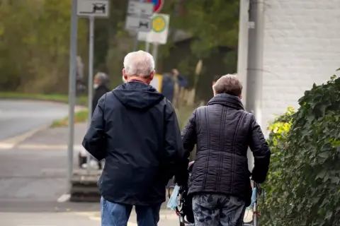 Starsza para spaceruje, być może zastanawiając się nad swoją przyszłością i tym, czy średnia emerytura w Niemczech wystarczy na spokojne życie.