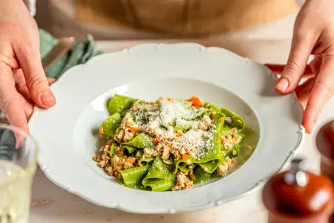 Grüne Bandnudeln mit einem herzhaften ragu bianco, bestreut mit Parmesan.