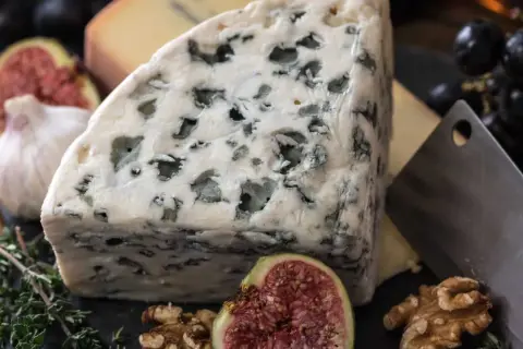 Un trozo de queso azul, con sus vetas verdes, parece un queso que huele mal. Acompañado de higos, nueces y ajo.