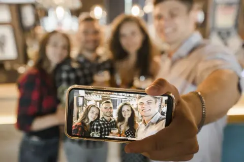 Grupa przyjaciół robi sobie zdjęcie grupowe telefonem. Oto jak zrobić selfie telefonem, by uchwycić wspólne chwile.
