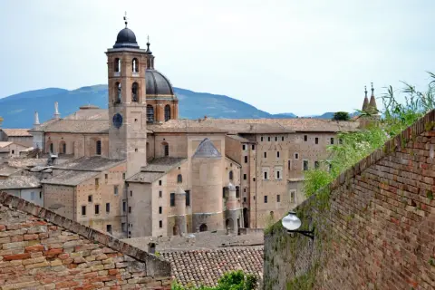 La maestosa corte di Urbino, con il suo campanile e la cupola, si staglia contro le colline.
