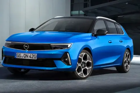 Błękitny Opel Astra Sports Tourer z czarnym dachem i felgami stoi przed nowoczesnym budynkiem.