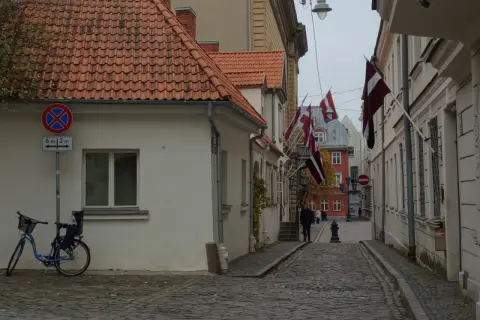 Urokliwa uliczka w Rydze, z łotewskimi flagami i brukowaną nawierzchnią. Idealne miejsce, by poczuć atmosferę miasta i zobaczyć, co zobaczyć w Rydze.