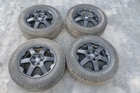 Cztery czarne felgi z oponami Yokohama Geolandar A/T, idealne do Subaru Outback Wilderness, gotowe na każdą przygodę.