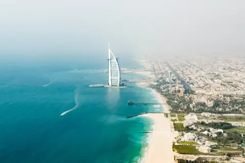 Widok z lotu ptaka na plaże w Dubaju, z charakterystycznym hotelem Burdż al-Arab i turkusową wodą.