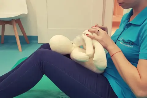 Terapeuta ćwiczy pozycję do karmienia butelką z pluszowym niemowlakiem.