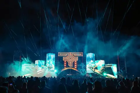 Nocny festiwal muzyczny z laserami i ekranami LED. Tłum ludzi bawi się przy muzyce na żywo.