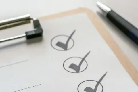 Klemmbrett mit Stift und abgehakten Punkten auf einer Checkliste.